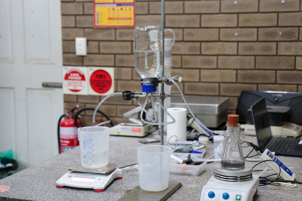 A laboratory table featuring a beaker, a scale, and a laptop, illustrating a scientific workspace setup.