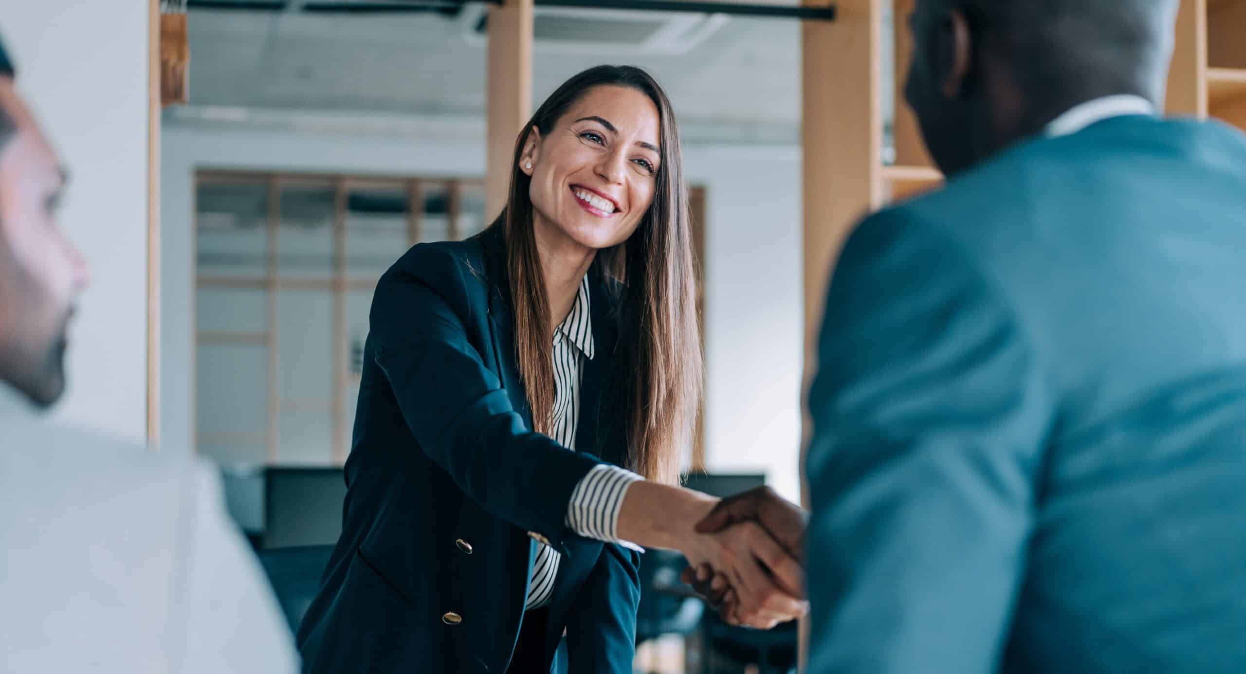 Business people shaking hands in the office. Group of business persons in business meeting. Three entrepreneurs on meeting in board room. Corporate business team on meeting in modern office. Female manager discussing new project with her colleagues. Company owner on a meeting with two of her employees in her office.