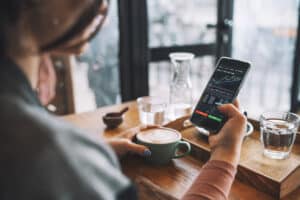 Unrecognisable woman using smartphone buy cryptocurrency at a coffee shop, blockchain investment, decentralise and Stock market concept.